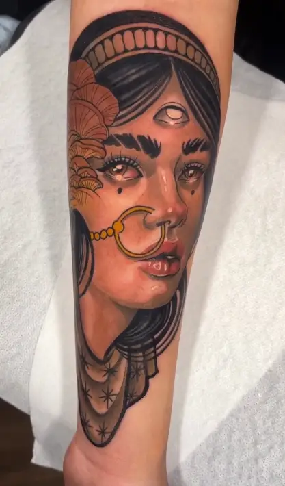 Rostro femenino místico tatuado en el antebrazo